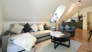 Ett modernt vardagsrum i loftstil med en soffa, ett soffbord och en matplats.