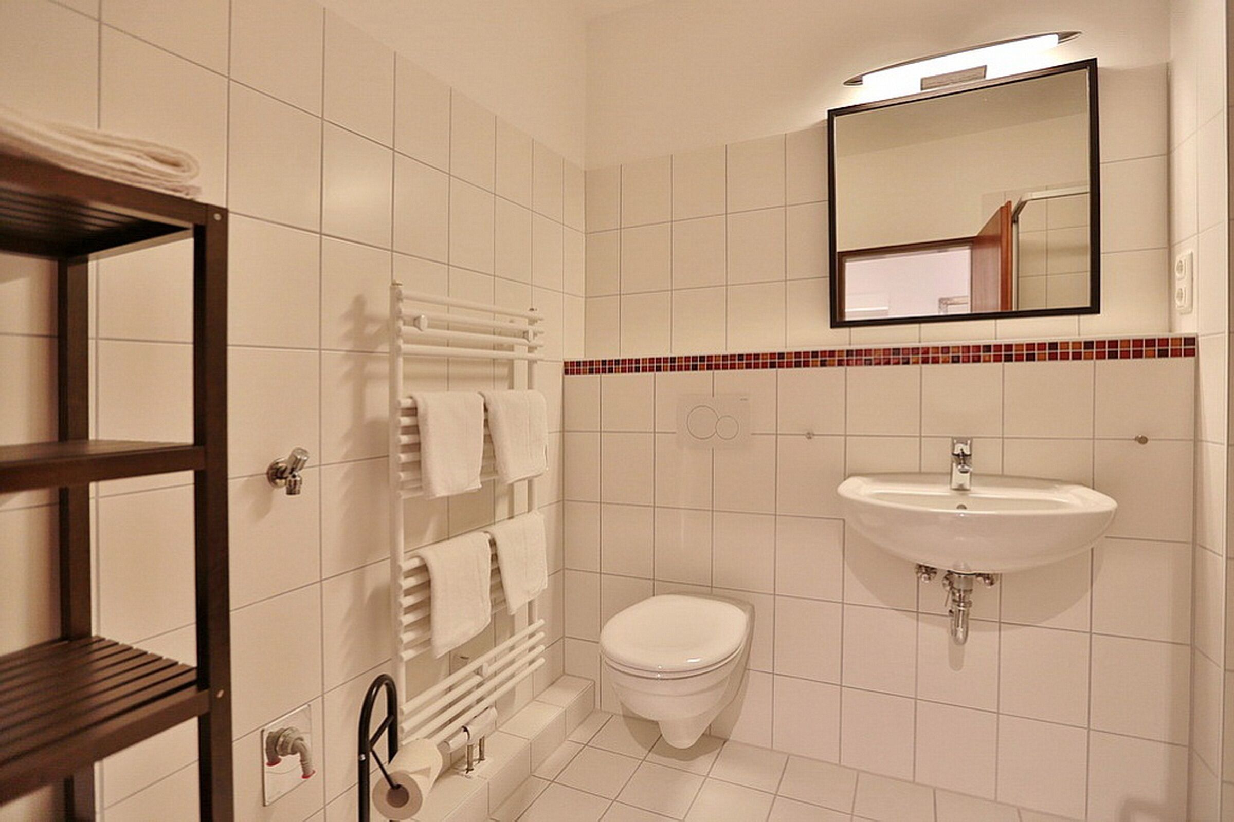 Une salle de bain moderne équipée de toilettes, d’un lavabo et d’un porte-serviettes.