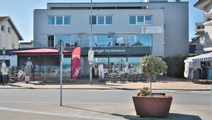 Un bâtiment moderne avec une enseigne indiquant « Junge Die Bäckerrei » et un espace extérieur aménagé avec des sièges.