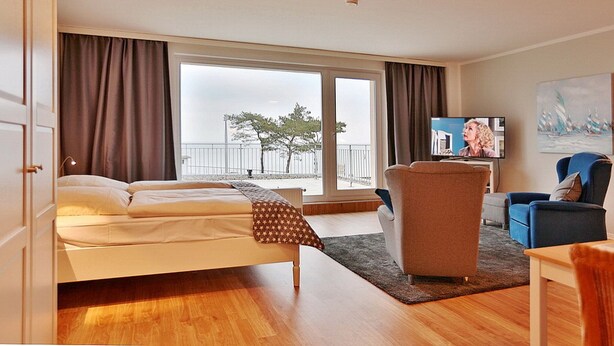Une chambre d’hôtel avec un lit, une télévision, une chaise et un tableau au mur.