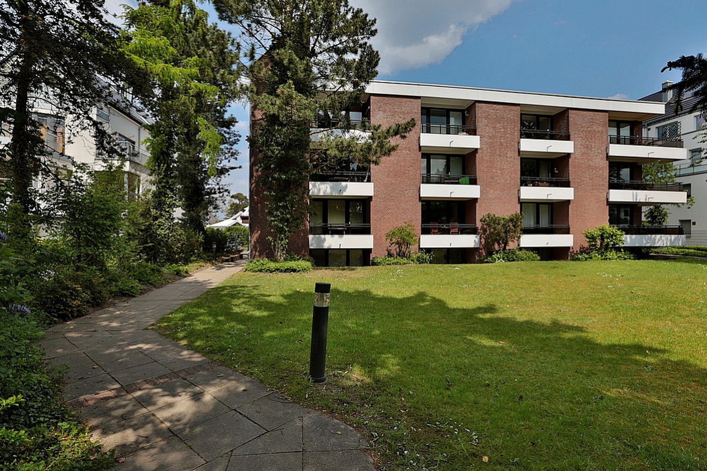 A modern multi-story building with a brick facade, large windows, and balconies.