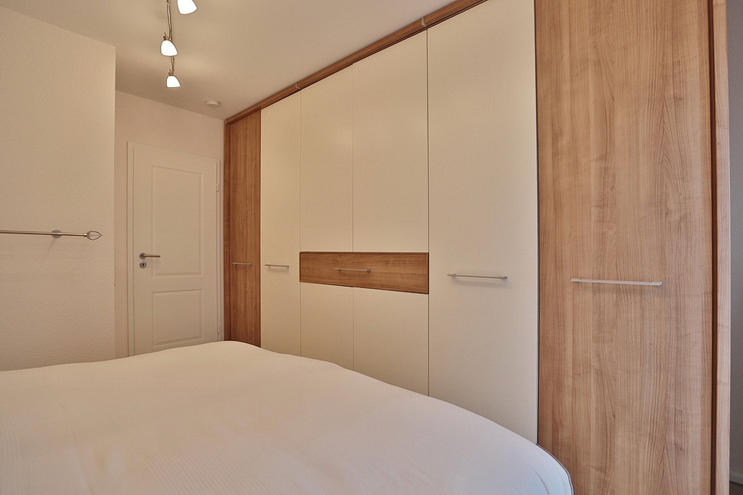 Quarto com cama, guarda-roupa de madeira e uma porta.