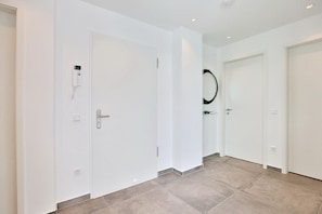 Un couloir avec des portes blanches, un système de sécurité et un miroir au mur.
