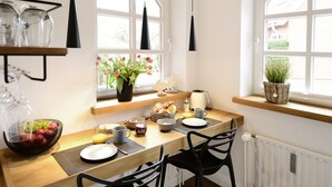 A bright kitchen with a wooden table, black chairs, and a window with a view of a brick building. - Am Rosenhain Appartement 3 Hygge (Timmendorfer Strand)