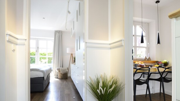A modern kitchen with black chairs, a dining table, and a window with natural light. - Am Rosenhain Appartement 3 Hygge (Timmendorfer Strand)