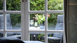 A room with a large window, a bed, and a table with a bottle and glass. - Am Rosenhain Appartement 3 Hygge (Timmendorfer Strand)
