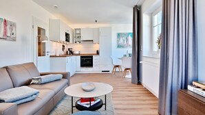Uma sala de estar moderna com um sofá, mesa de centro e vista para a cozinha.