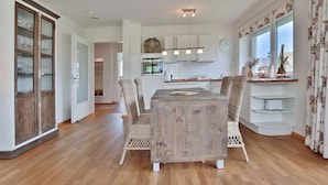 Una cocina moderna con una mesa de comedor de madera, sillas de mimbre y un horno empotrado.