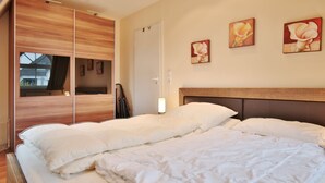 Un dormitori amb un llit gran, un armari de fusta i dos quadres a la paret.