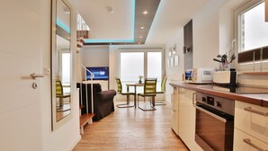Une cuisine moderne avec un coin repas, un plancher en bois et une vue sur l’extérieur.