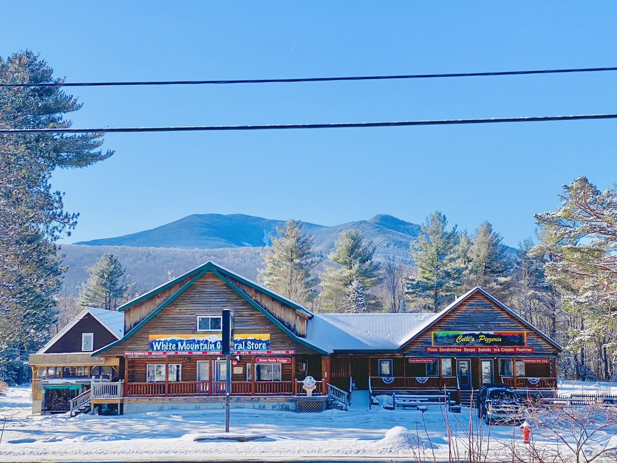 Un edificio a due piani con un'insegna per White Mountain General Store e Celli's Pizza.