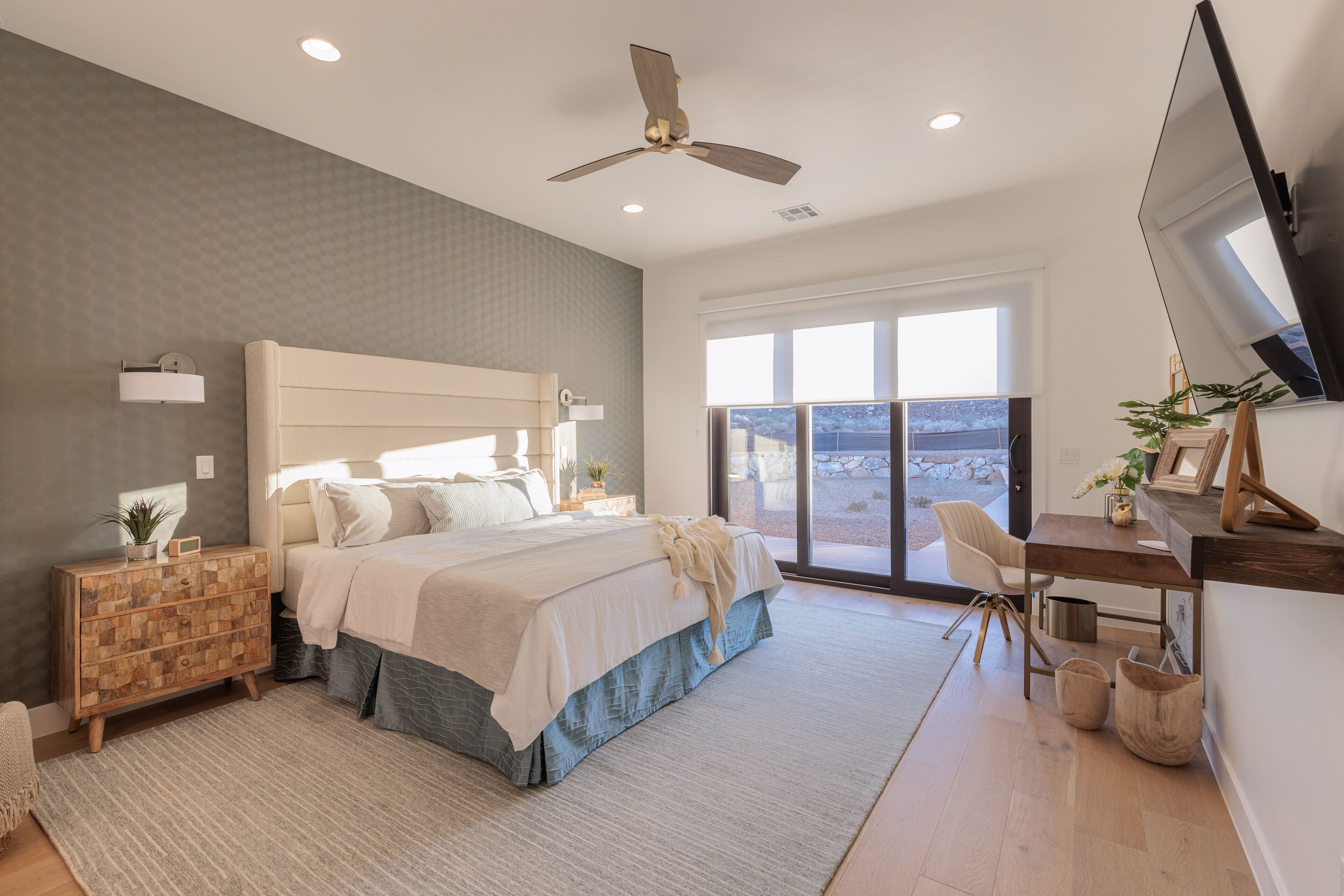 Un dormitorio moderno con una cama grande, un escritorio y un ventilador de techo.