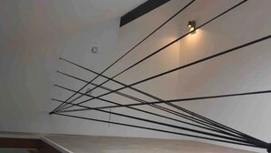 Een modern interieur met een schuine plafond, een dakraam, en een reeks zwarte lijnen die samenkomen bij een lamp.
