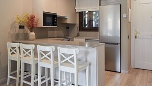 Una cocina moderna con una isla central, taburetes de bar, un refrigerador y un microondas.