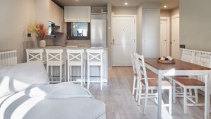 Una cocina moderna con armarios blancos, un comedor con sillas blancas y una zona de estar acogedora con un sofá blanco.