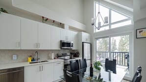 A modern kitchen with white cabinets, stainless steel appliances, and a dining area with a glass table and chairs.