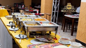 Un'area buffet con diverse postazioni, una varietà di piatti e utensili, all'Hotel Bukandula.