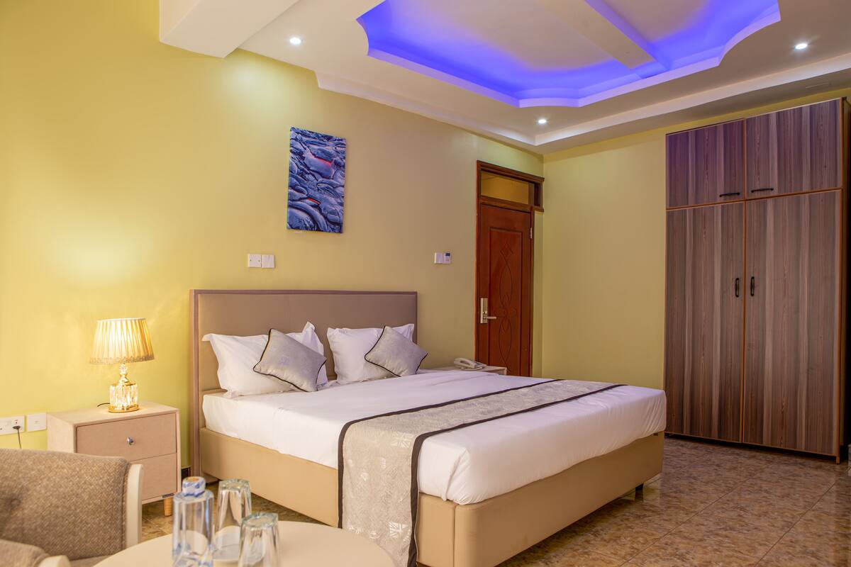 A hotel room with a bed, bedside table, lamp, and wardrobe.