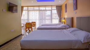 Una camera d'albergo con due letti, una televisione, una scrivania e una finestra con tende.