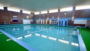 Une piscine intérieure avec des lignes de démarcation bien visibles pour les couloirs, un plongeoir et un poste de surveillance pour le sauveteur.