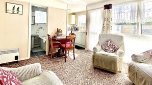Un salon chaleureux comprenant un coin repas, une cuisine et un balcon agrémenté de rideaux.
