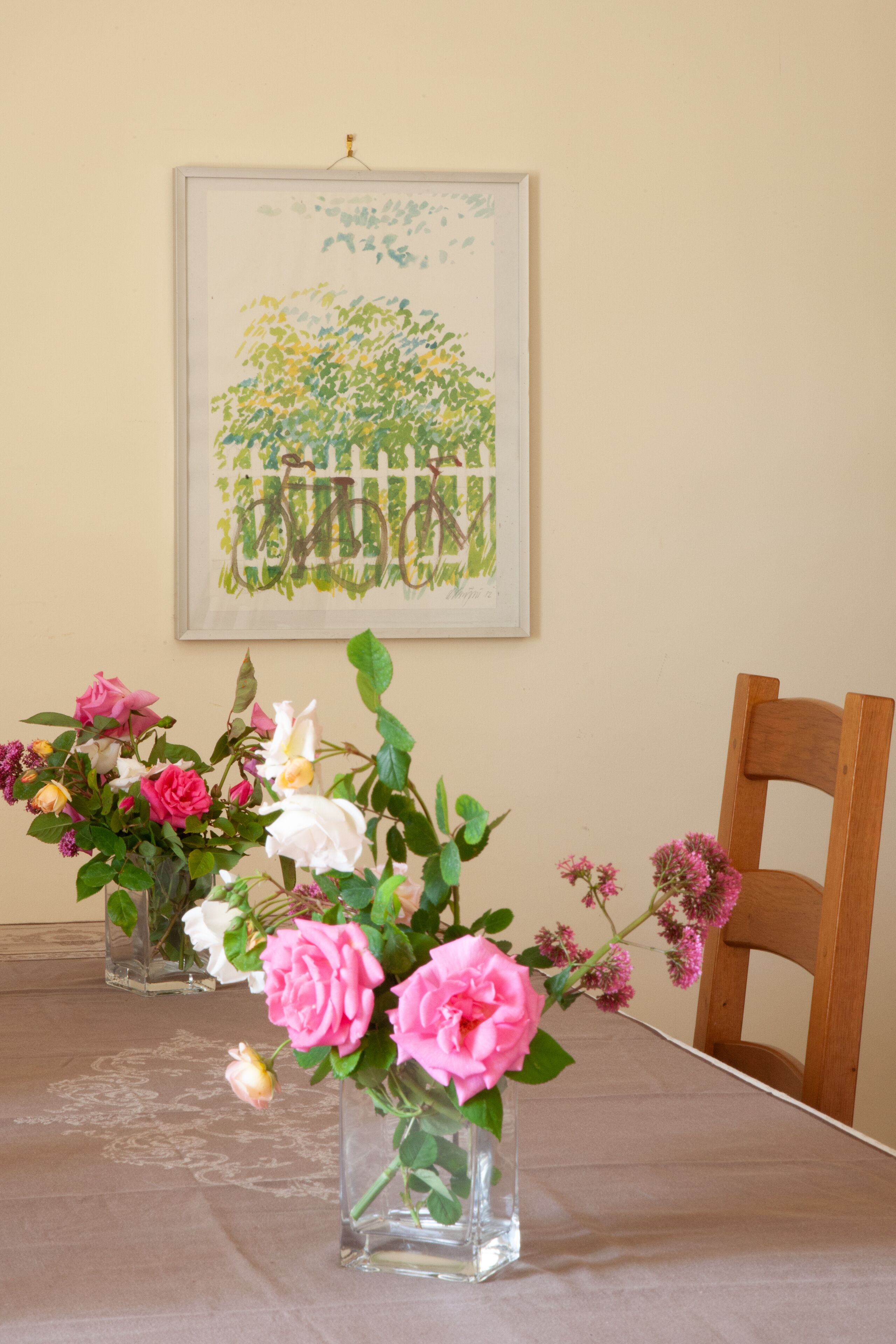 Una mesa de comedor con un jarrón de flores y un cuadro en la pared.