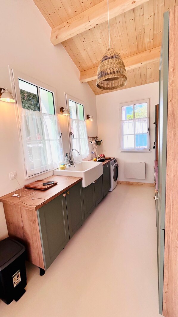 Una cocina moderna con armarios de madera, un lavamanos grande y una lámpara colgante.