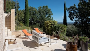 A patio with two lounge chairs, a white sofa, and potted plants. - Exceptional Luberon location - Private swimming pool (Cucuron)