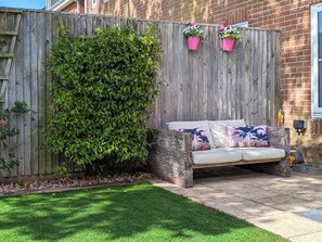 A garden with a wooden fence, a grassy lawn, and a sofa with floral cushions. - 3 bedroom accommodation in St Helens, near Ryde (St Helens, near Ryde)