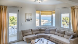 A modern living room with a large sectional sofa, a coffee table, and a view of the sea through large windows. - A seafront villa with swimming pool (Achlia)