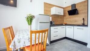 Una cucina moderna con mobili bianchi, forno a microonde integrato e cappa aspirante nera.