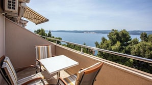 Un balcone con tavolo e sedie, affacciato su un tratto d'acqua e la terraferma in lontananza.