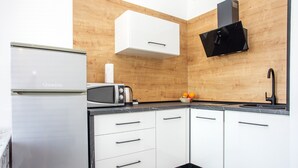 Una cucina compatta con mobili bianchi, un piano di lavoro nero, un forno a microonde, un tostapane e una cappa aspirante nera.