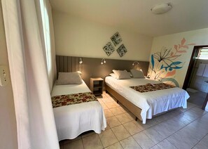 Une chambre d’hôtel avec deux lits, une table de chevet et un mur orné d’œuvres d’art décoratives.
