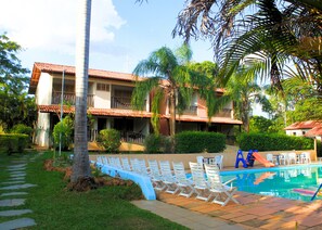 Un hôtel doté d’une piscine, de chaises longues et de palmiers.