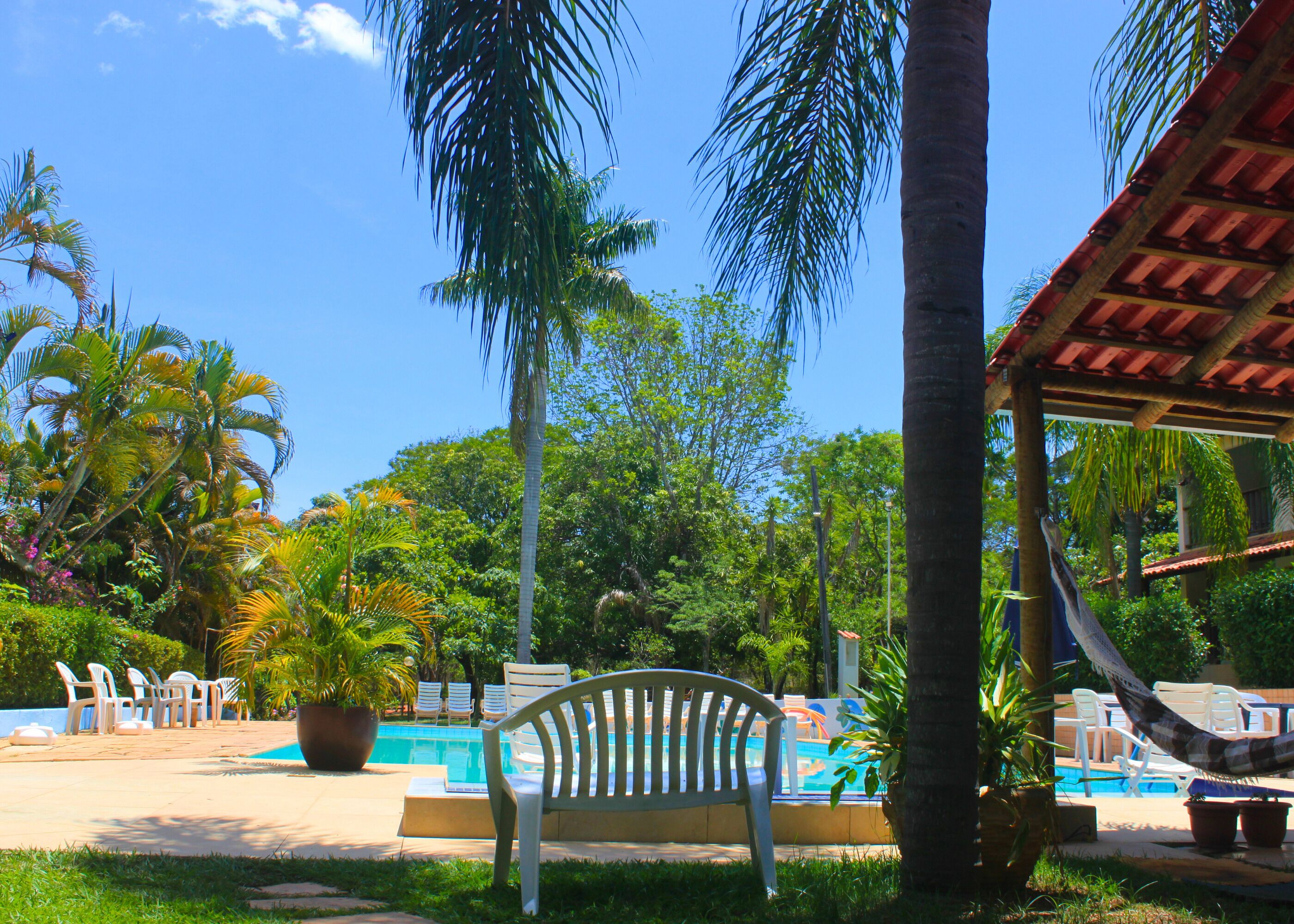 Un área de piscina con sillas de descanso, un banco y una hamaca.