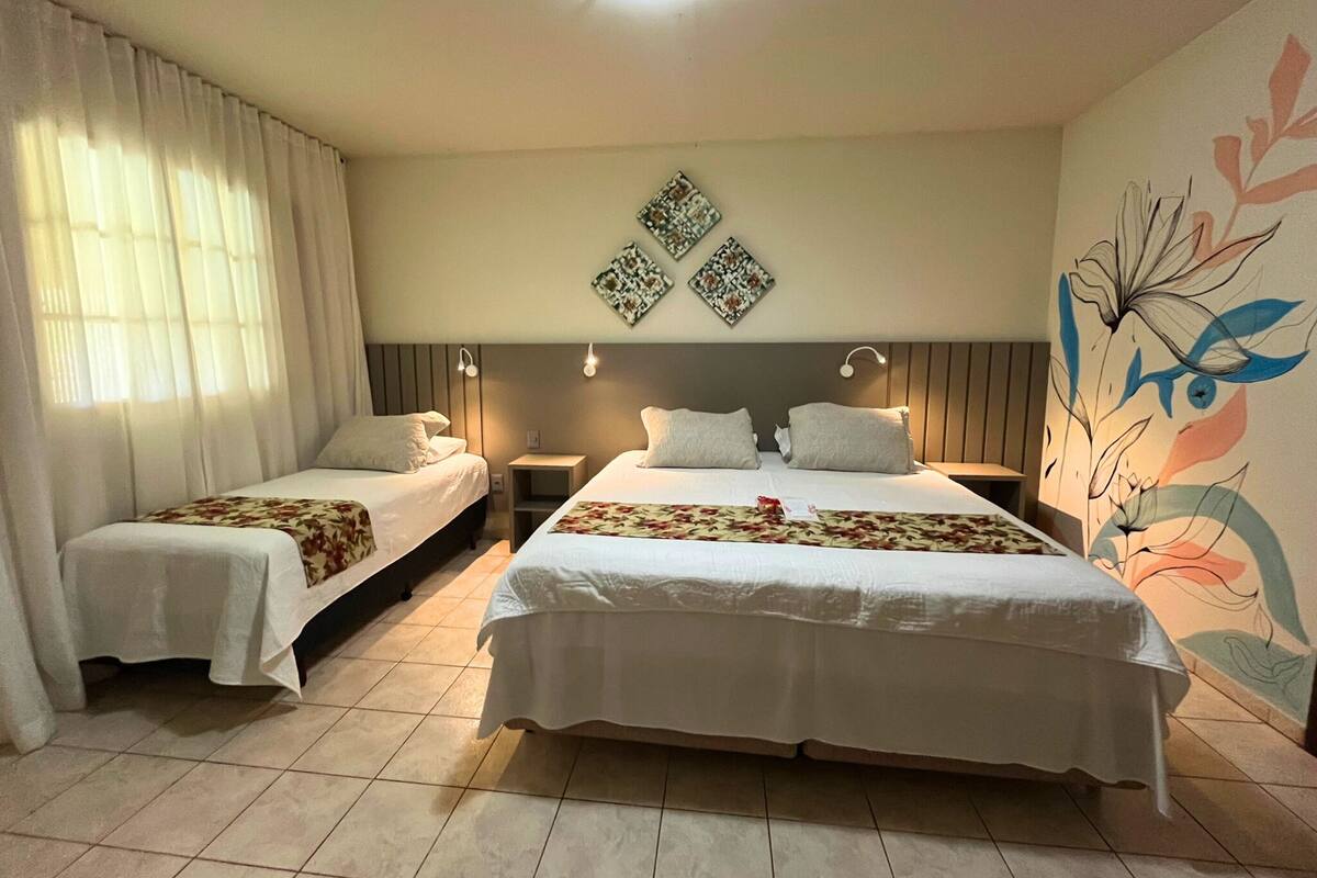 Una habitación de hotel con dos camas, un amplio mural floral y una lámpara en el techo.