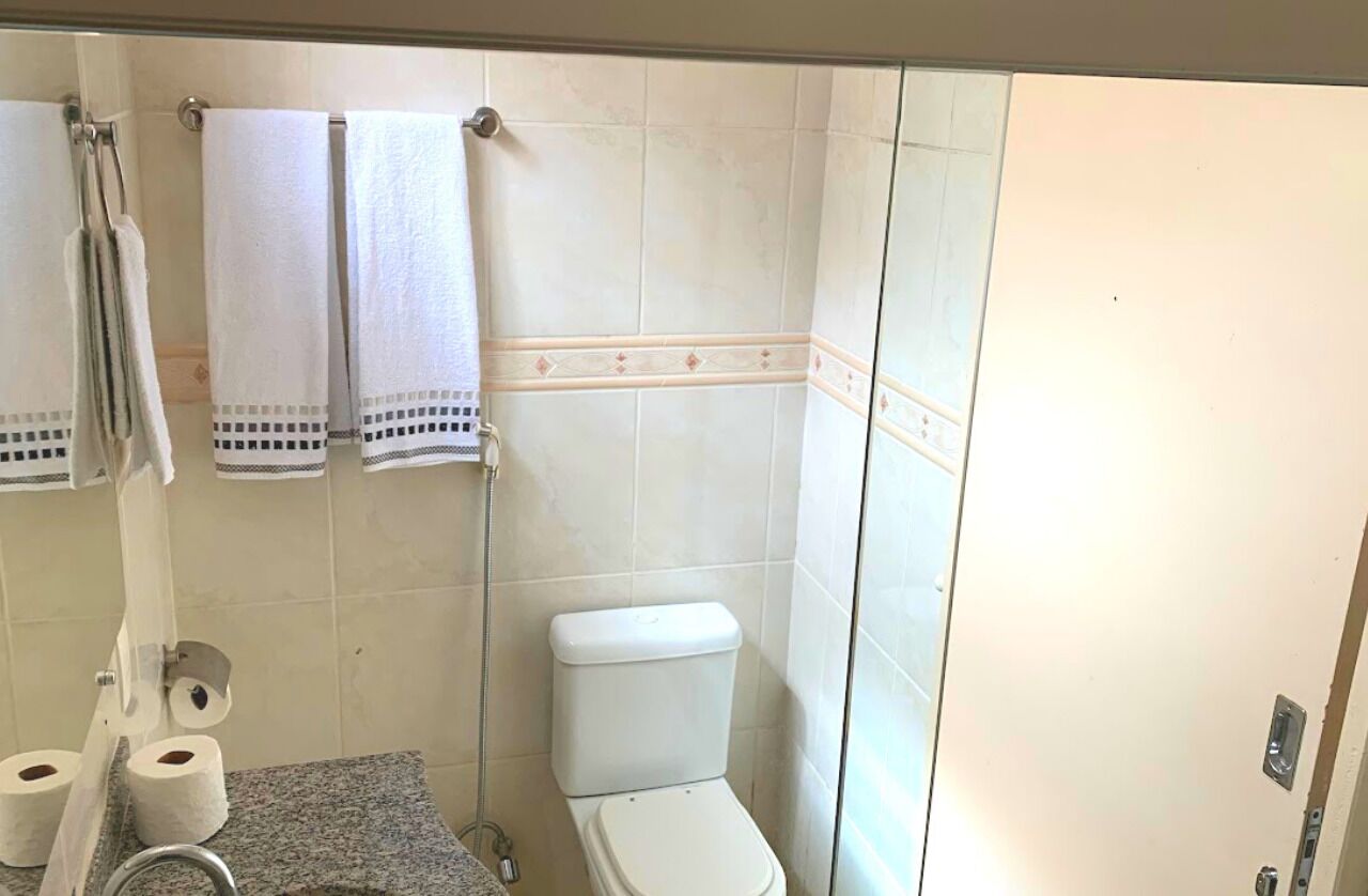 Une salle de bain avec des toilettes, deux serviettes suspendues à un porte-serviettes et deux rouleaux de papier toilette posés sur le comptoir.
