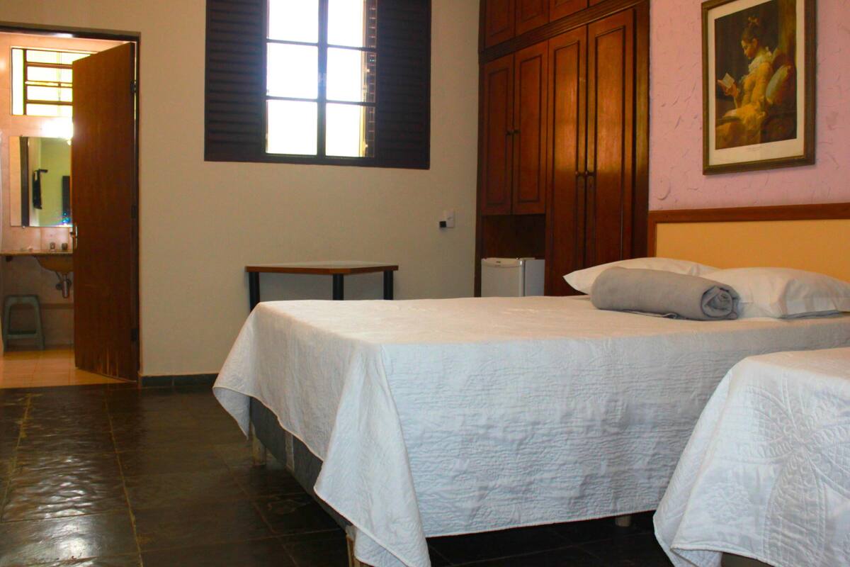 Habitación de hotel con dos camas, un armario de madera y un cuadro en la pared.