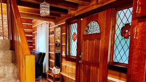 Una escalera de madera que lleva a un cuarto con puerta de madera, un banco y una alfombra.