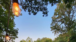 Una terraza al aire libre con mobiliario de mimbre, una chimenea y guirnaldas de luces.