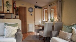 Un salon confortable avec un canapé, des fauteuils, une table à manger et une horloge au mur.