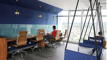 A modern office with a blue accent wall, multiple workstations, and a view of the city through large windows.