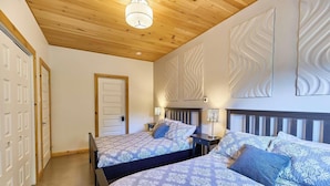 A bedroom with two beds, wooden ceiling, and decorative wall panels.