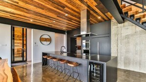 A modern kitchen with a central island, bar stools, and a stainless steel refrigerator. - L’Eaurizon | Private Spa & St. Lawrence View (La Malbaie)