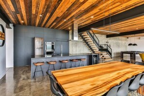 A modern kitchen with a central island, bar stools, and a staircase leading to an upper level.