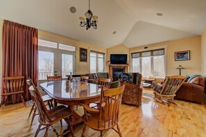 Un salon spacieux avec une grande table à manger, des sièges confortables, une cheminée et un téléviseur.