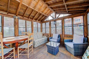 A wooden-paneled room with a table and chairs, a sofa, and a wicker coffee table.
