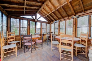 A rustic wooden room with large windows, wooden tables and chairs, and a sign reading 'BIERE FROIDE'.