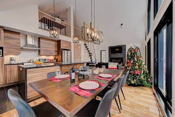 Une cuisine moderne avec un coin repas, des meubles en bois, une cuisinière encastrée et un sapin de Noël.